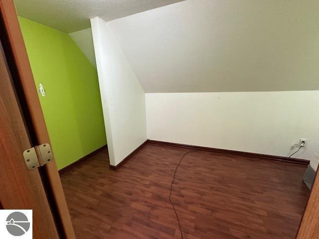 additional living space featuring vaulted ceiling, wood finished floors, and baseboards