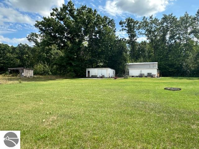 view of yard featuring a detached garage, a storage shed, and an outdoor structure