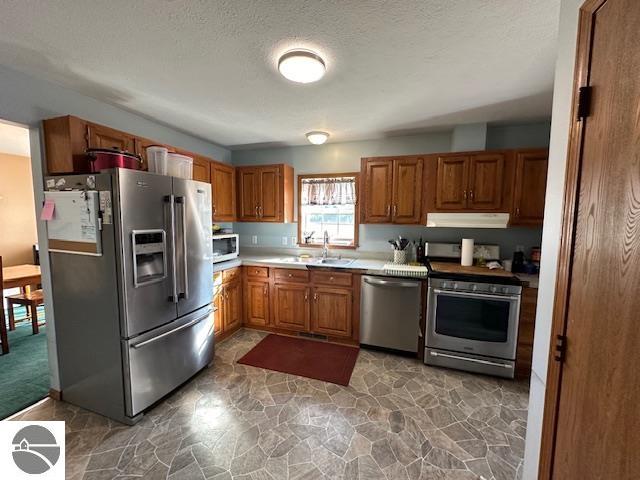 kitchen featuring a textured ceiling, stainless steel appliances, and sink