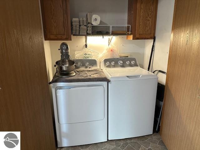 clothes washing area featuring dark tile patterned flooring, cabinets, and washing machine and clothes dryer