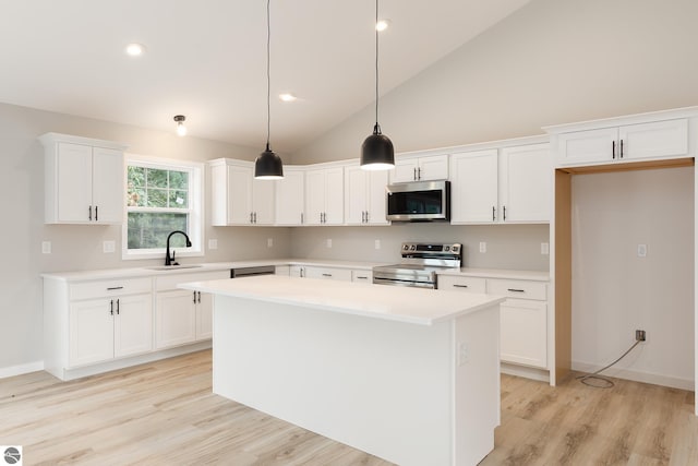 kitchen with stainless steel appliances, light countertops, white cabinets, a sink, and a kitchen island