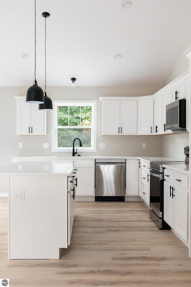 kitchen with light wood-style flooring, white cabinetry, light countertops, appliances with stainless steel finishes, and hanging light fixtures