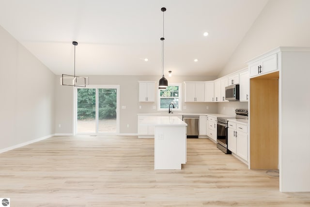 kitchen with a center island, stainless steel appliances, light countertops, light wood-style flooring, and white cabinetry