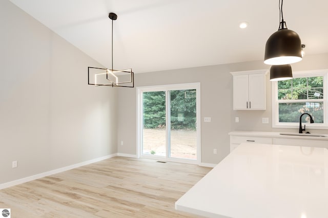 kitchen featuring light countertops, a sink, light wood-style flooring, and white cabinets