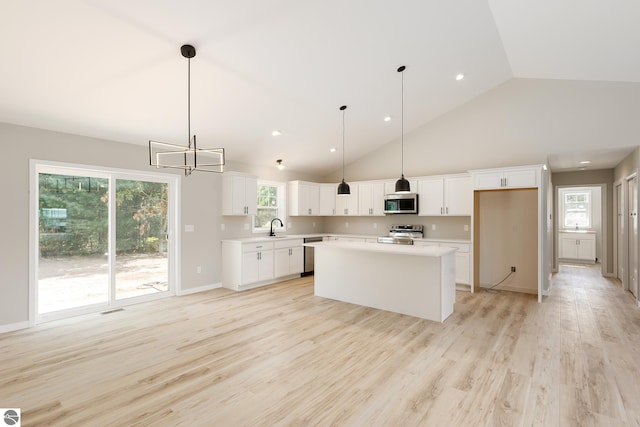 kitchen featuring appliances with stainless steel finishes, a kitchen island, decorative light fixtures, and white cabinets