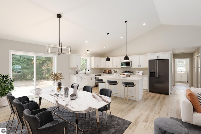 dining space with high vaulted ceiling, light wood finished floors, recessed lighting, and an inviting chandelier