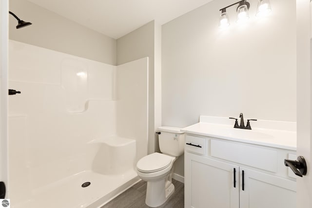 bathroom featuring wood finished floors, vanity, toilet, and walk in shower