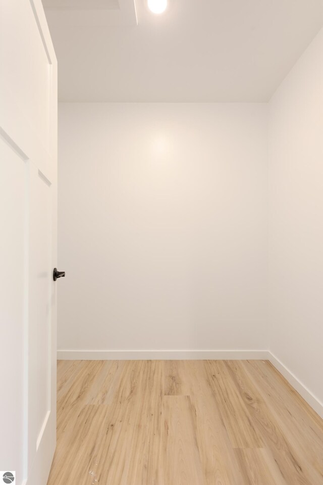 spare room featuring baseboards and light wood-style floors