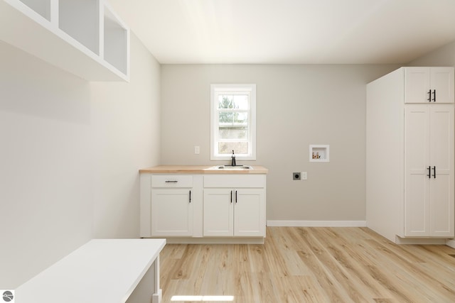 clothes washing area with hookup for a washing machine, a sink, baseboards, light wood-type flooring, and electric dryer hookup