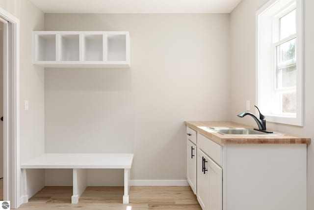 interior space featuring light wood-style floors, baseboards, and a sink