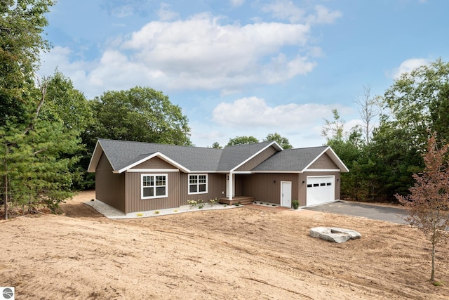 single story home with driveway, roof with shingles, and an attached garage