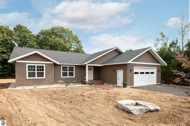 single story home featuring aphalt driveway, an attached garage, and a shingled roof