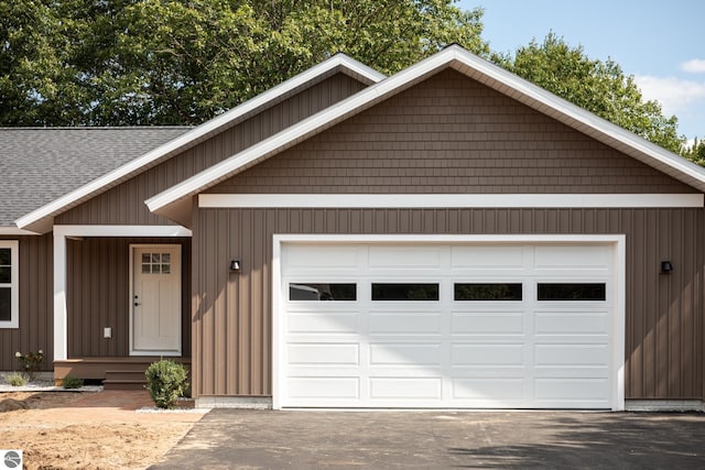 ranch-style house featuring a garage, aphalt driveway, and a shingled roof