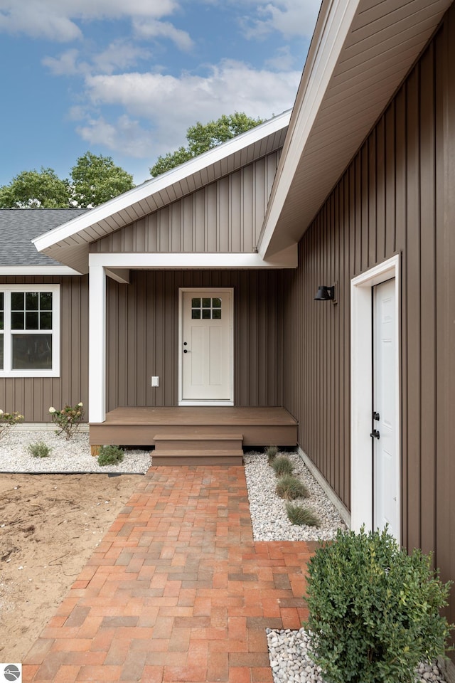 doorway to property featuring board and batten siding and a shingled roof