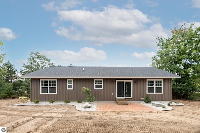 rear view of house featuring entry steps, roof with shingles, and a patio