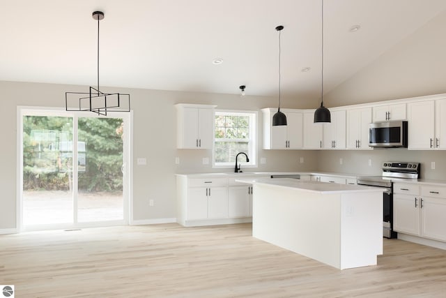 kitchen featuring stainless steel appliances, a kitchen island, white cabinets, light countertops, and pendant lighting