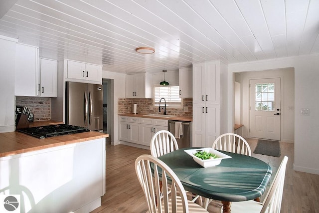 dining room featuring light wood-type flooring, wood ceiling, and sink