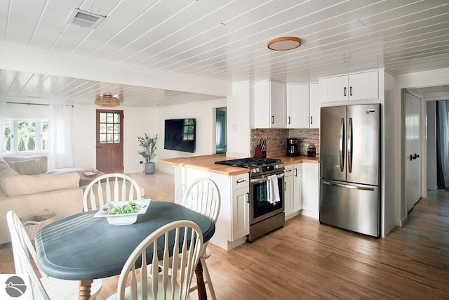 kitchen with dark wood-type flooring, stainless steel appliances, white cabinetry, and wooden counters