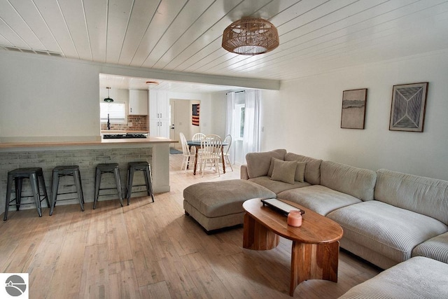 living room with light wood-type flooring, sink, and wooden ceiling