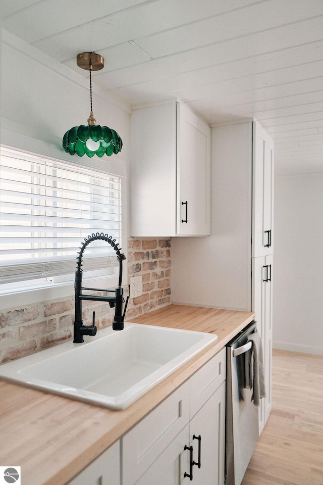 kitchen with white cabinets, stainless steel dishwasher, sink, and hanging light fixtures