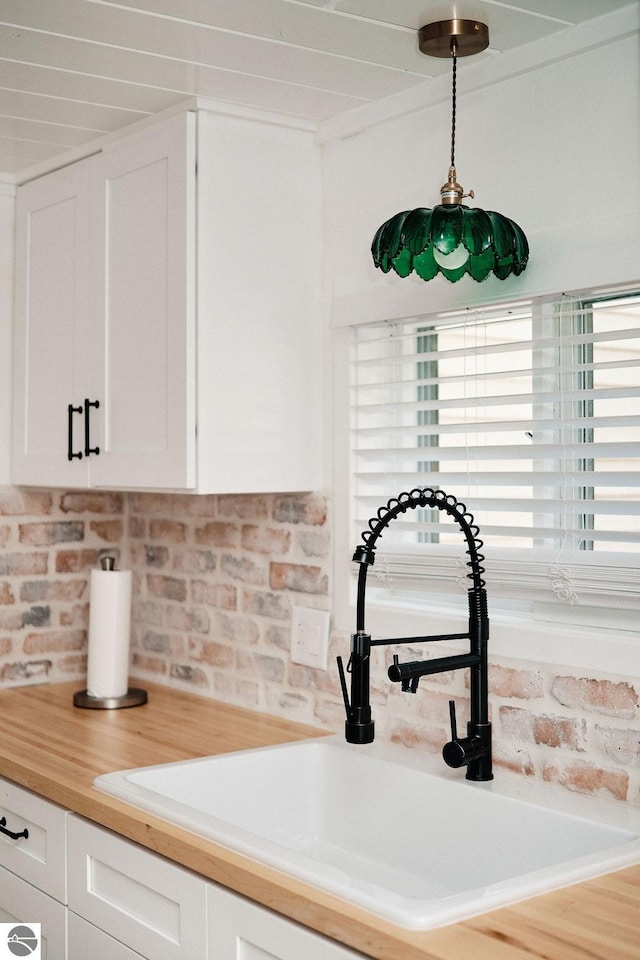 interior space featuring decorative light fixtures, crown molding, white cabinetry, and sink