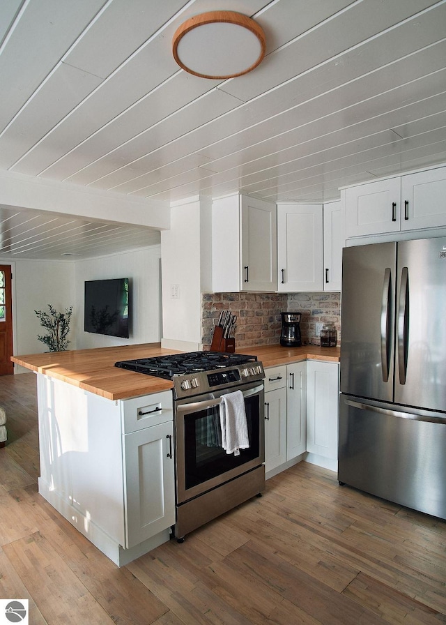 kitchen with butcher block countertops, white cabinets, stainless steel appliances, and light wood-type flooring