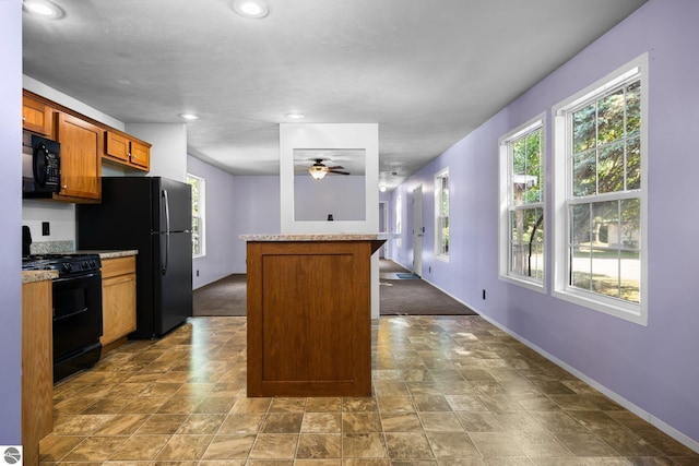 kitchen with black appliances, plenty of natural light, ceiling fan, and a kitchen island