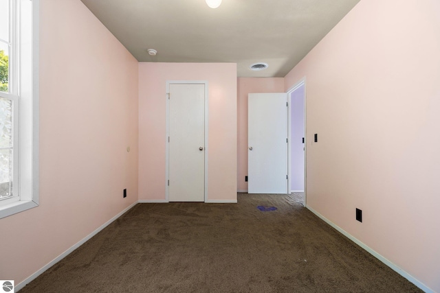 unfurnished bedroom featuring dark carpet and a closet