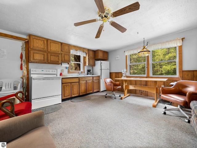 kitchen featuring white appliances, wood walls, ceiling fan, pendant lighting, and a textured ceiling