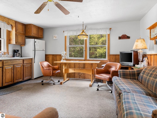 interior space with a textured ceiling, ceiling fan, and wooden walls