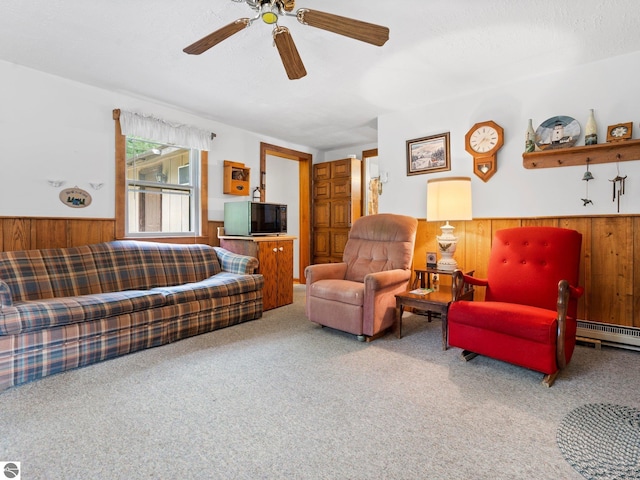 carpeted living room with a textured ceiling, a baseboard radiator, ceiling fan, and wooden walls