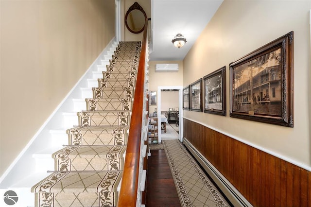 stairs with a baseboard heating unit, wood walls, hardwood / wood-style floors, and a wall unit AC