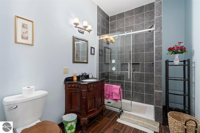 bathroom featuring vanity, toilet, wood-type flooring, and a shower with door