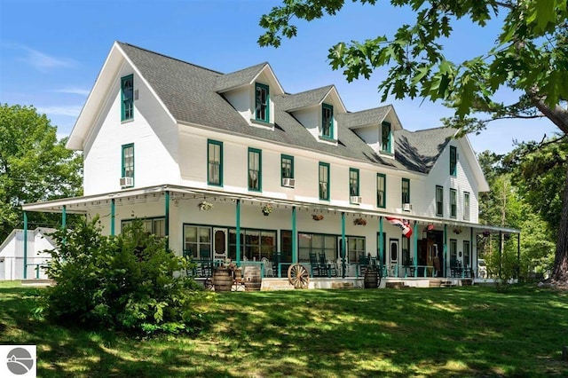 rear view of property featuring a porch and a yard