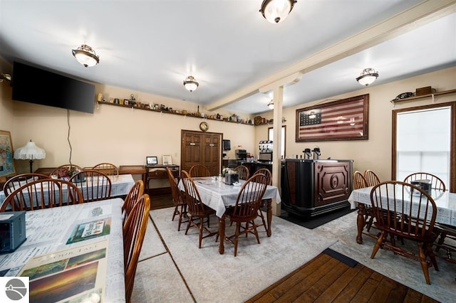 dining area with wood-type flooring and beamed ceiling