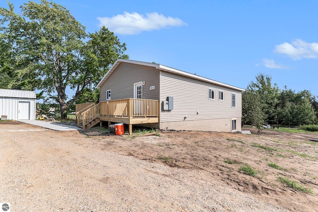 rear view of house with a garage, a deck, and an outbuilding