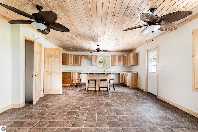 kitchen featuring wood ceiling, a kitchen island, a breakfast bar area, and ceiling fan