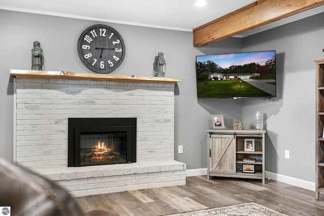 living room featuring wood-type flooring, beamed ceiling, and a fireplace