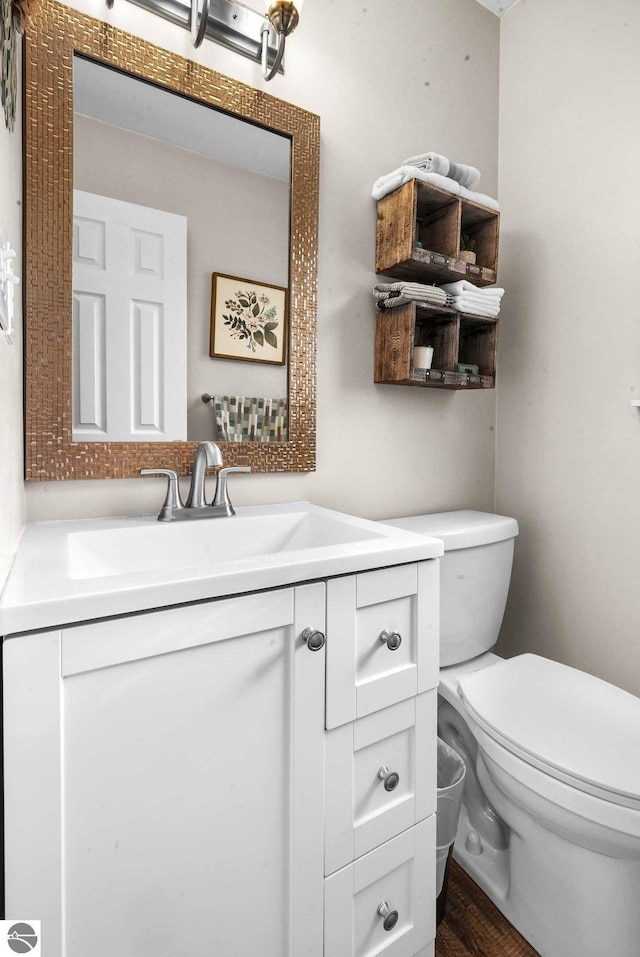 bathroom with wood-type flooring, vanity, and toilet