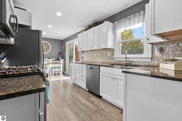 kitchen with tasteful backsplash, sink, white cabinets, light hardwood / wood-style flooring, and appliances with stainless steel finishes