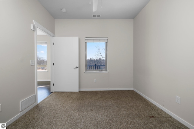 empty room featuring plenty of natural light, ceiling fan, and carpet flooring