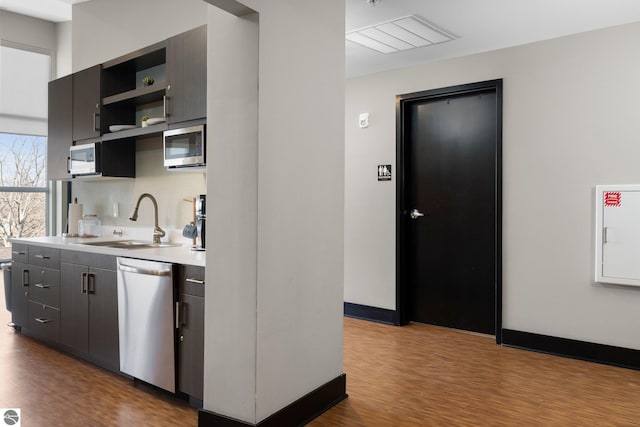 kitchen with appliances with stainless steel finishes, sink, and light hardwood / wood-style floors