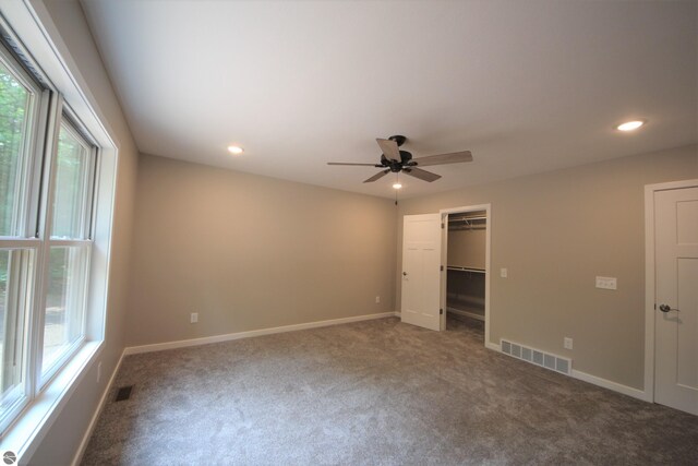 unfurnished bedroom featuring a walk in closet, ceiling fan, and carpet