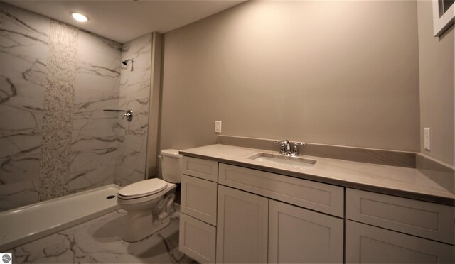 bathroom featuring vanity, tiled shower, and toilet