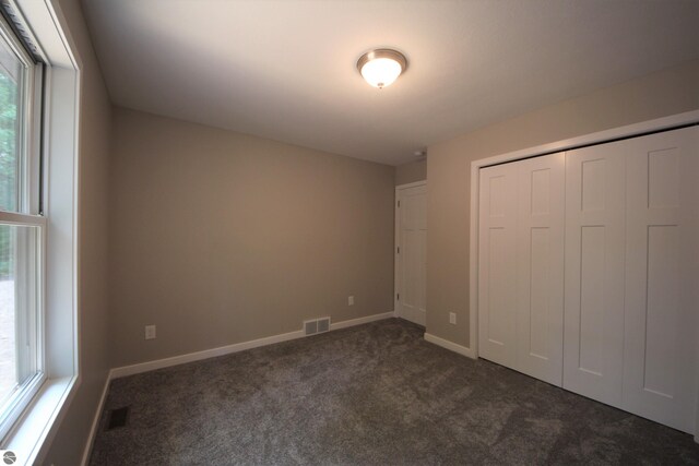 unfurnished bedroom featuring a closet and dark colored carpet