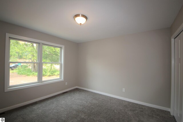 unfurnished room with dark carpet