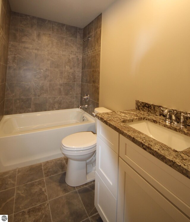 full bathroom with vanity, tiled shower / bath, tile patterned floors, and toilet