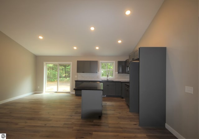 kitchen featuring tasteful backsplash, sink, gray cabinetry, a center island, and dark wood-type flooring