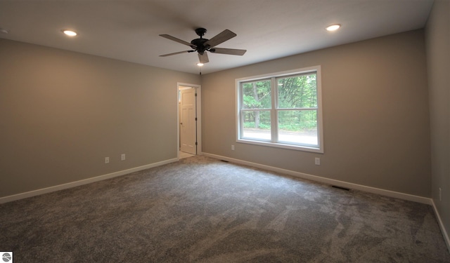 spare room featuring ceiling fan and dark carpet