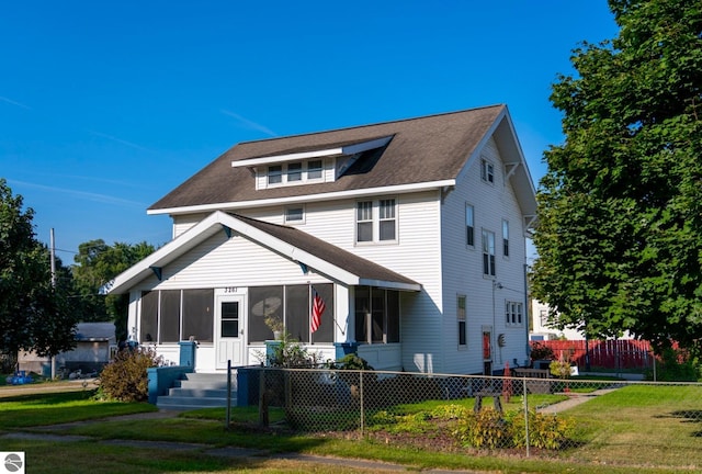 view of front of home with a sunroom and a front lawn